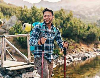 A smiling hiker in the forest crossing a river
