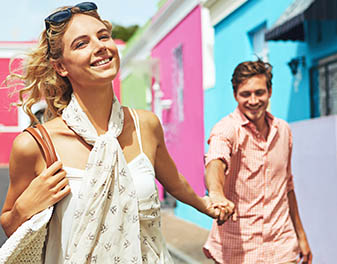 A smiling couple roaming through a street with brightly coloured buildings